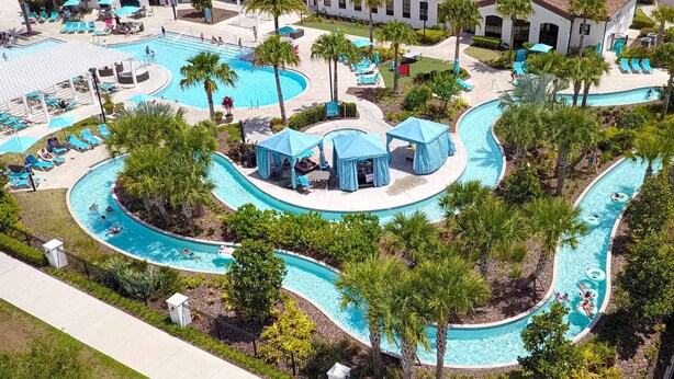 Vista aérea de um resort com várias piscinas, áreas de descanso e palmeiras.