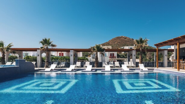 A swimming pool with lounge chairs, a mountain backdrop, and a building with a red roof. - Naxos Grand Hotel (Stelida)
