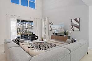 A spacious living room with a grey sofa, a coffee table, and a TV mounted on the wall. - Chic 5Bed Retreat, Perfect for Family Getaways (Four Corners)