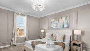 Una camera da letto con un letto grande, due comodini, un lampadario e una finestra con tende.