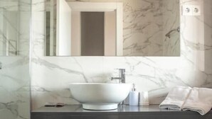A modern bathroom with a marble vanity, a large mirror, and a white sink. - Hotel Montañes (Suances)
