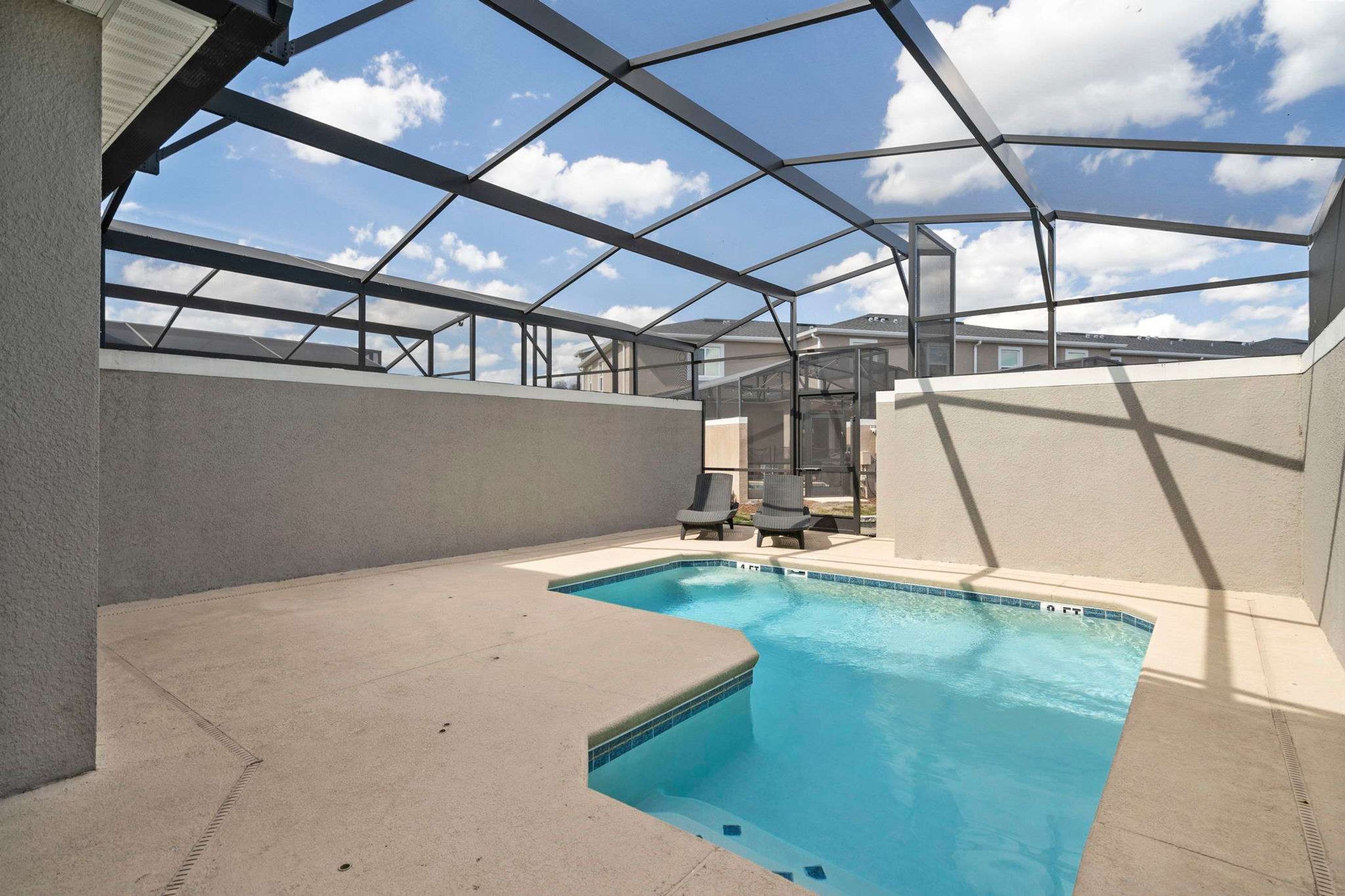 Une piscine dotée d’un toit en verre, entourée de chaises longues et offrant une vue dégagée sur le ciel.