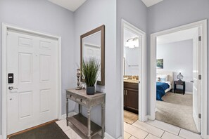 A hallway with a white door, a console table with a mirror, and a potted plant. - Spacious 4BR Townhome with Pool at Storey Lake (Kissimmee)