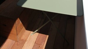 A small, light green table with a metal frame, positioned on a wooden deck adjacent to a white wall and a glass door. - T2 Panoramic sea and mountain view Beaurivage (Biarritz)