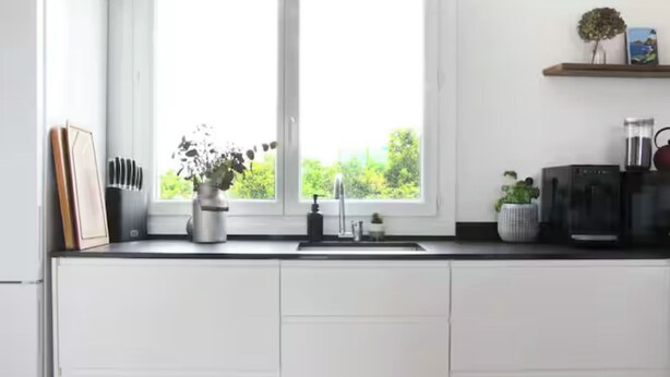 A modern kitchen with white cabinets, a window with a view of greenery, and a coffee machine. - T2 Panoramic sea and mountain view Beaurivage (Biarritz)