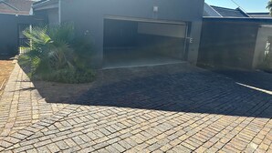 A modern building with a garage, paved driveway, and a small garden with palm plants. - Gorgeous 4-bedroom house in Meyersdal peaceful   neighborhood (Alberton)
