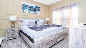Een slaapkamer met een houten bedframe, twee nachtkastjes, een bedtafel en een groot abstract schilderij aan de muur.