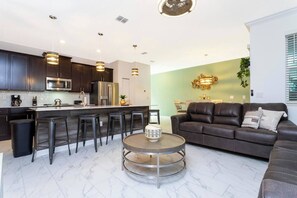 A modern kitchen with dark cabinets, stainless steel appliances, and a central island with bar stools. - Disney Area| Private Pool| Resort Waterpark 2956 (Kissimmee)