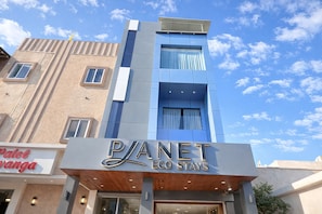 A hotel named 'Planet Eco Stays' with a modern facade, large windows, and a sign for 'Patel Vanga' adjacent to it. - Planet Eco Stays (Ujjain)