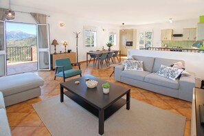 A spacious living room with a sofa, a coffee table, and a dining area with chairs and a table. - Wonderful bright, Spacious & Modern Holiday Home with Pool. Breathtaking Views (Comares)