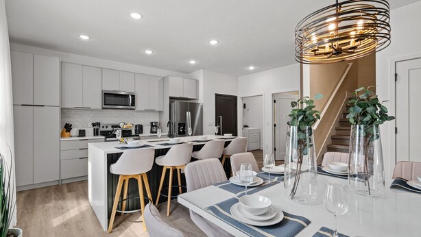 A modern kitchen with white cabinets, a central island, and a dining area with a white table and chairs. - Family Friendly Home with Themed Rooms & Pool (Four Corners)