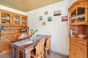 A wooden kitchen with a dining table, chairs, cabinets, and wall-mounted pictures. - Apartment 'Ferienhof Knudsen, Seehase' with Shared Terrace, Shared Garden and Wi-Fi (Pellworm)