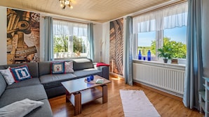 Ett modernt vardagsrum med en soffa, ett soffbord och utsikt över omgivningarna.