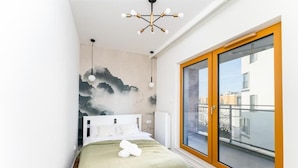 A bedroom with a bed, a large window, and a wall mural. - Malila Premium Apartments Rakowicka 437 (Kraków)