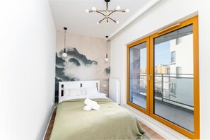 A bedroom with a bed, a large window, and a wall mural. - Malila Premium Apartments Rakowicka 437 (Kraków)
