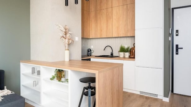 A modern kitchen with wooden cabinets, a central island with bar stools, and pendant lighting. - Malila Premium Apartments Rakowicka 437 (Kraków)