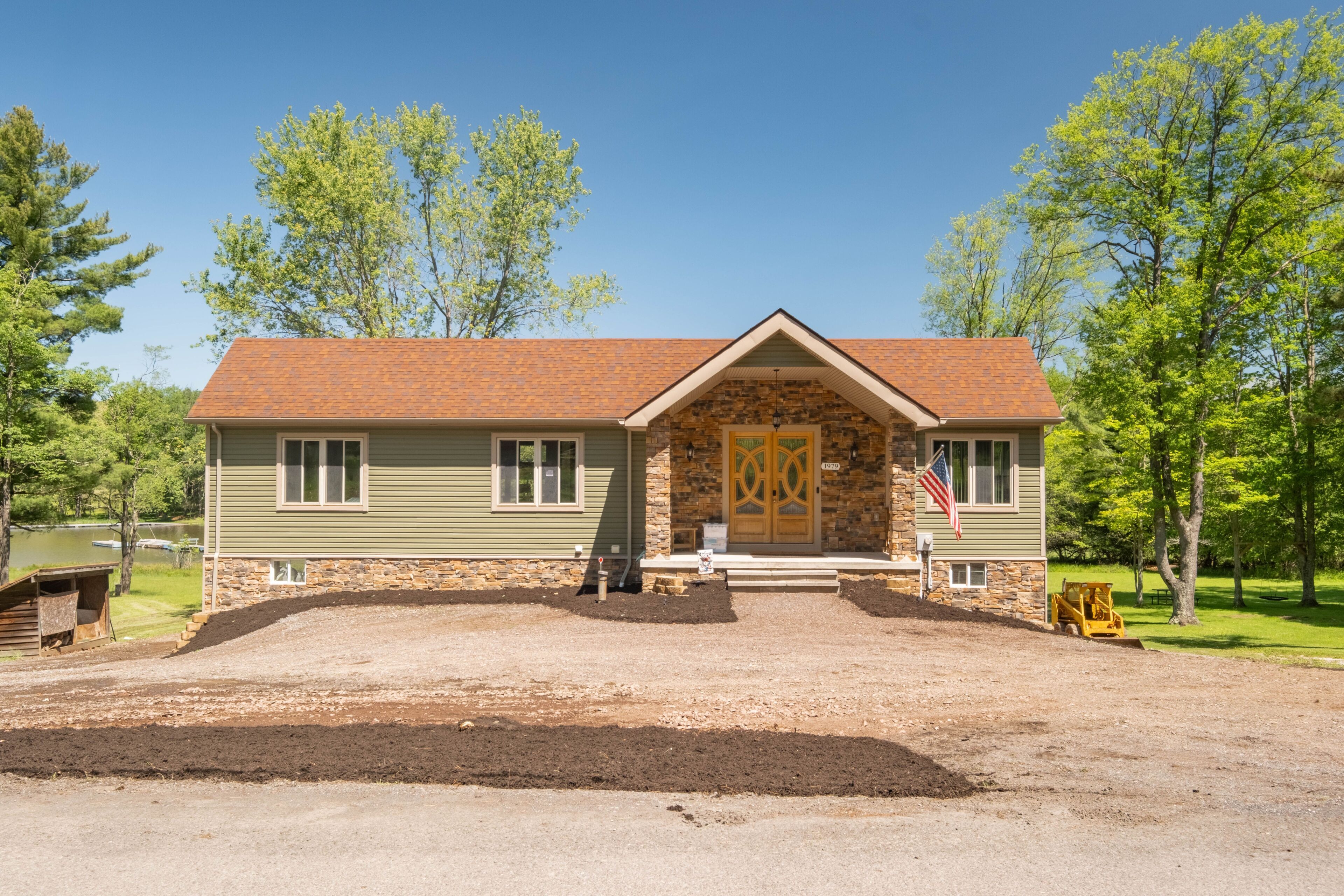A two-story building with a stone facade, a red-tiled roof, and a front porch.