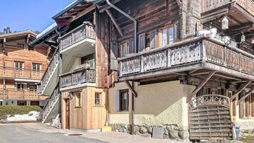 Ein mehrstöckiges Holzhaus mit Balkonen, einer Steinmauer und einer gut sichtbaren Eingangstür.