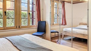Un dormitorio con un espejo grande, techo de madera y vista a zonas verdes.