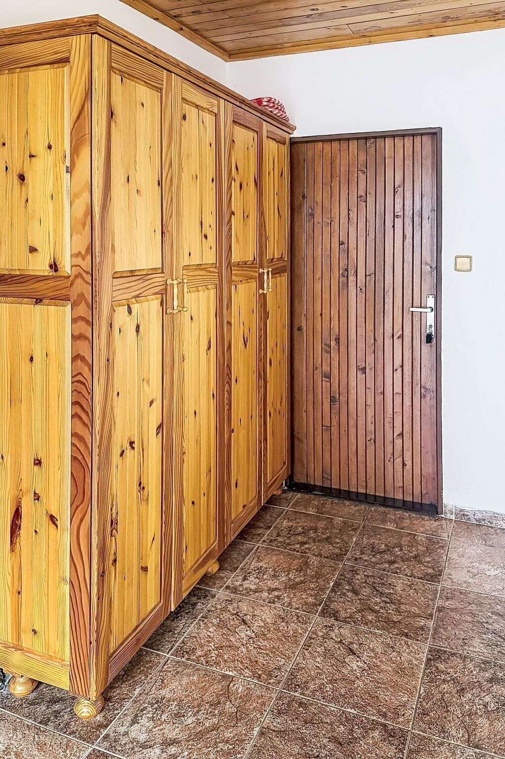 Quarto com armário de madeira, uma porta e piso ladrilhado.