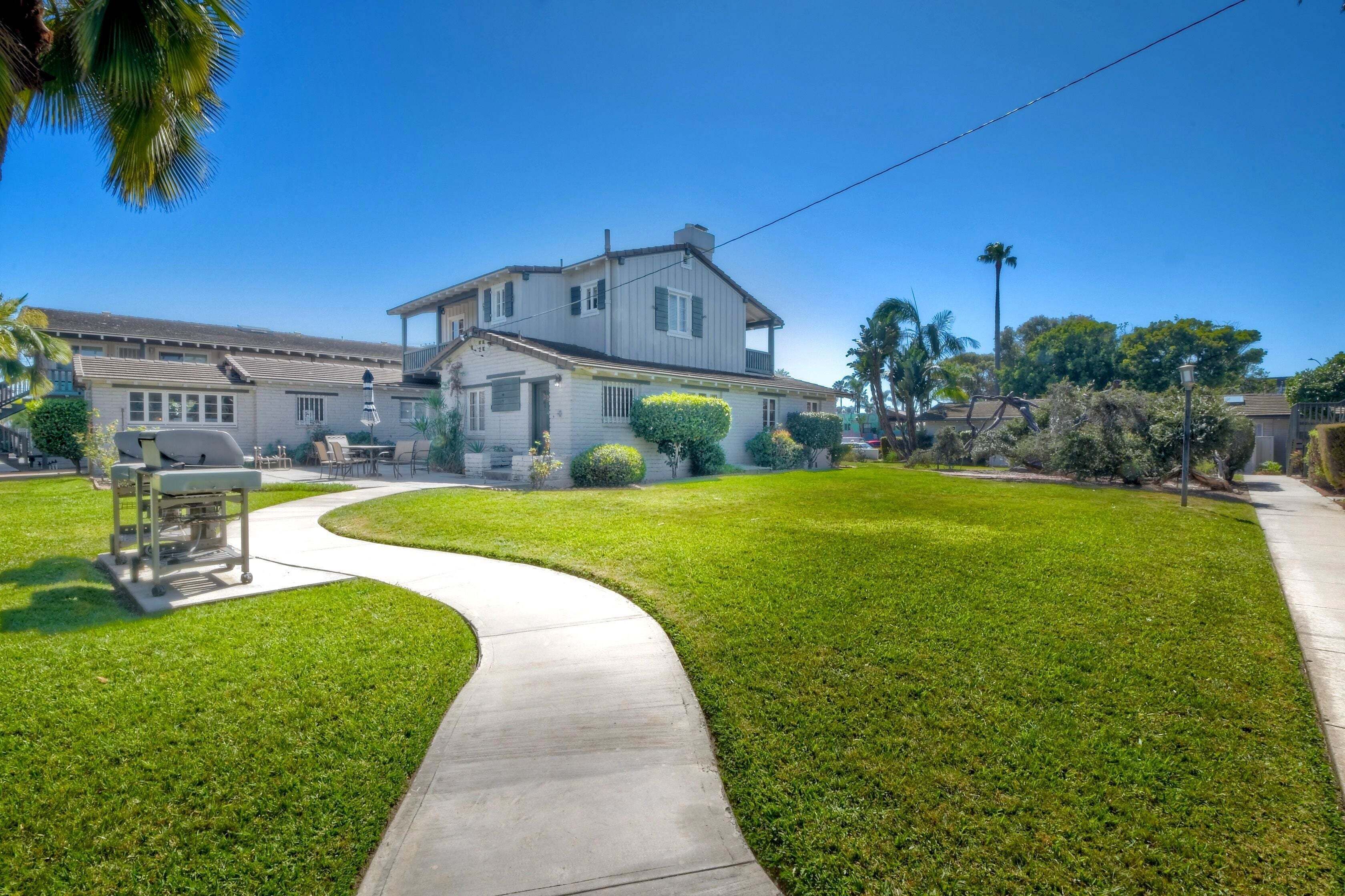 A two-story house with a curved driveway, a lawn, and a clear blue sky.