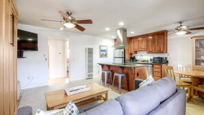 A modern kitchen with wooden cabinets, a central island, and bar stools. - 90 Walk Score l Private Patio | Steps to Beach & Dining | Parking (Carlsbad)
