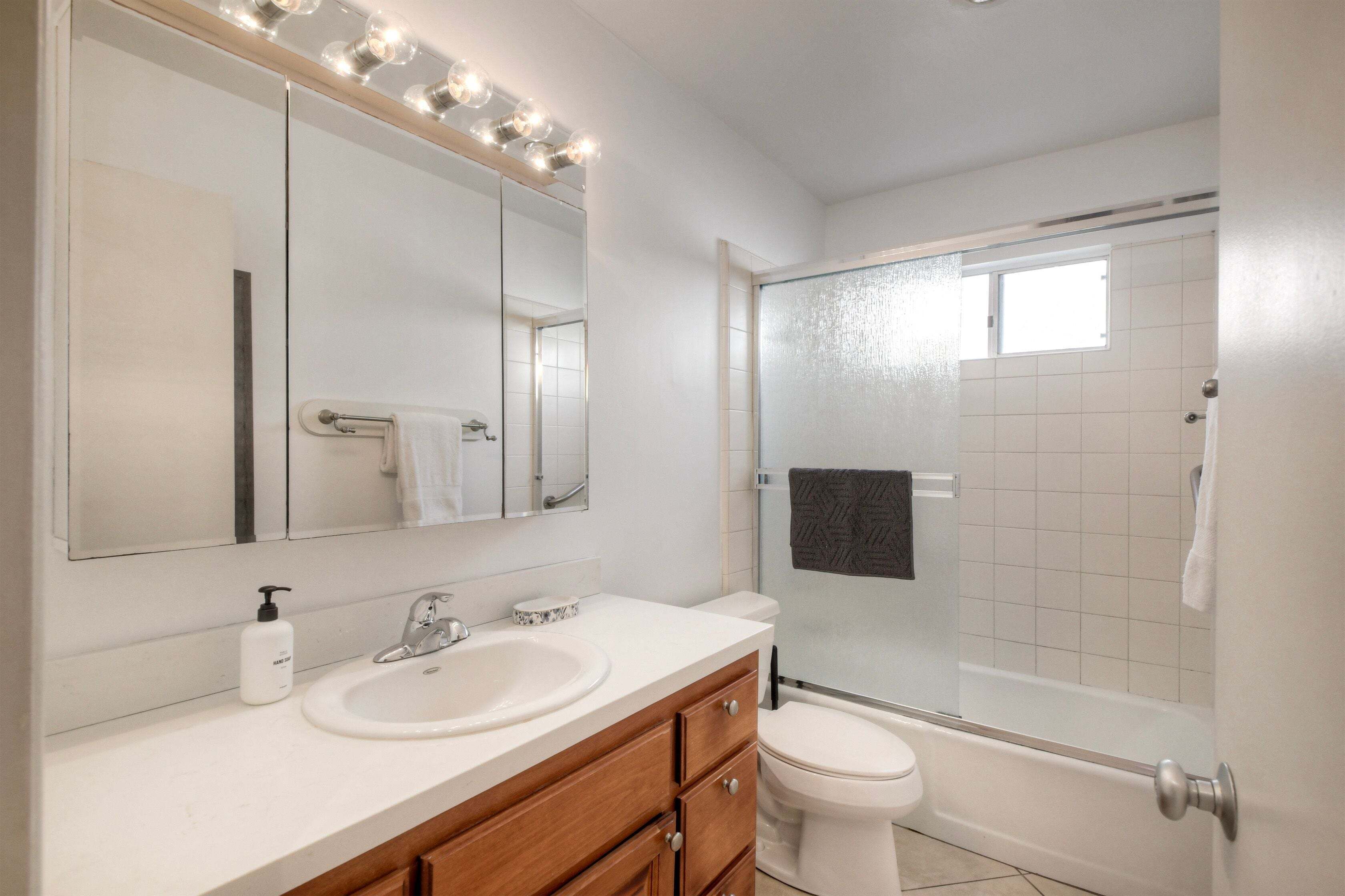 A bathroom with a sink, mirror, and shower.