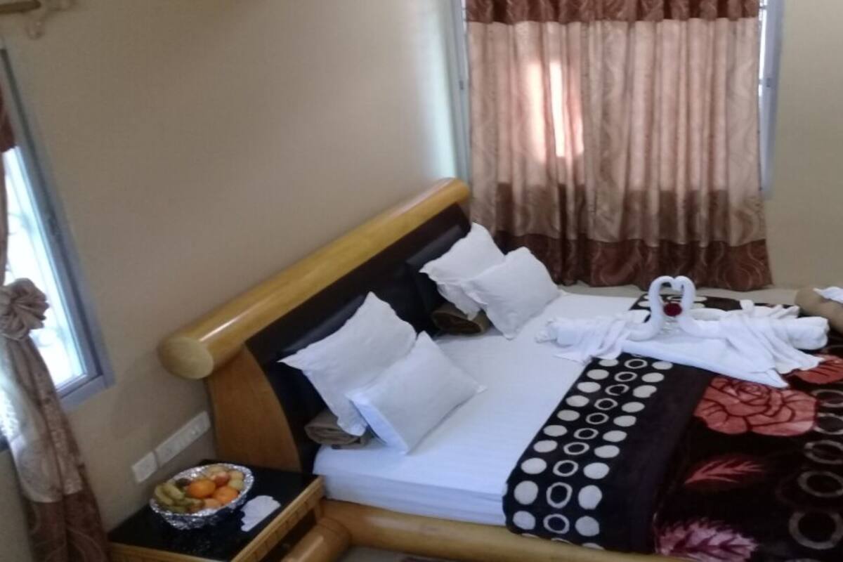 A neatly made bed with white linens, a floral-patterned blanket, and a tray with fruits on the side.