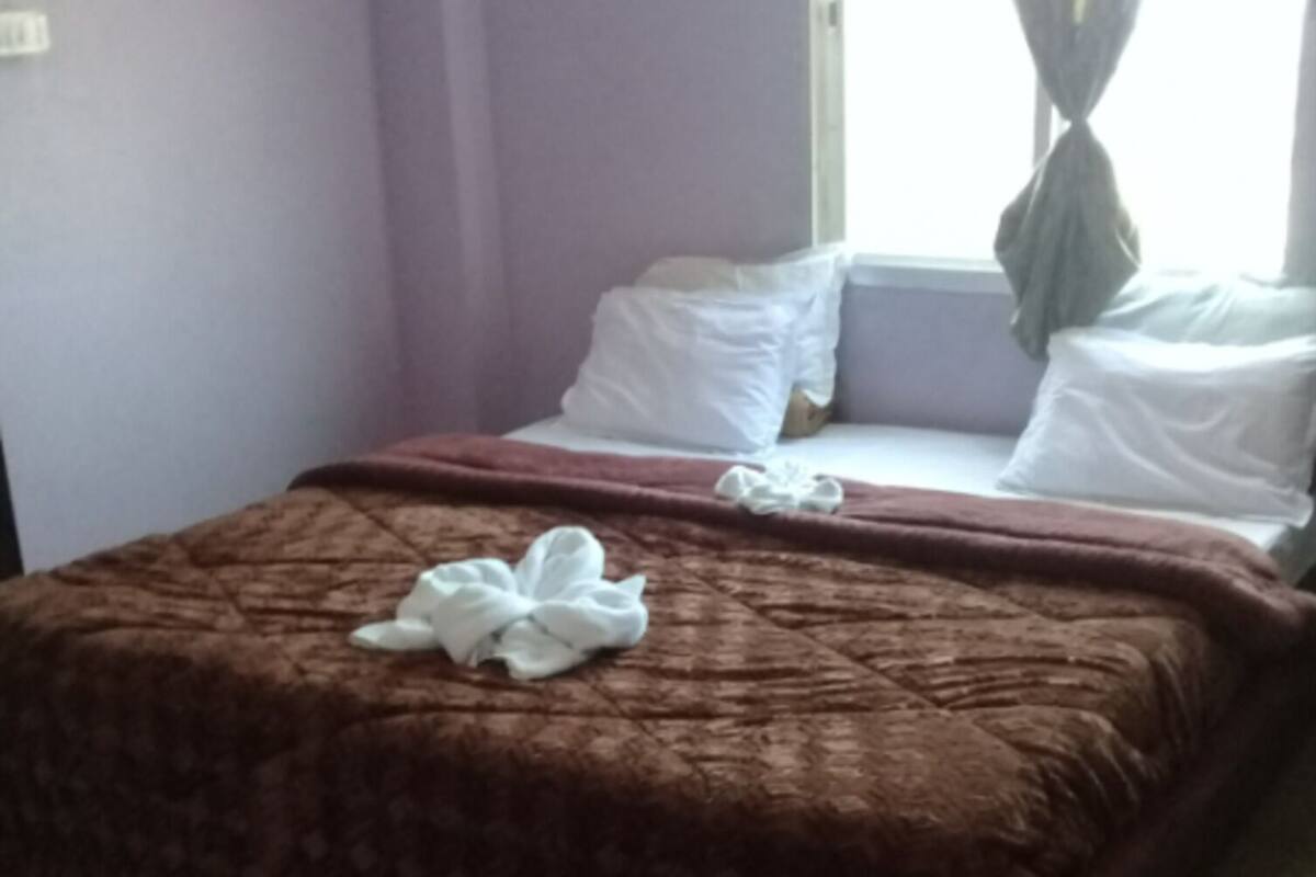 A neatly made bed with a brown patterned bedspread and a white towel on top.