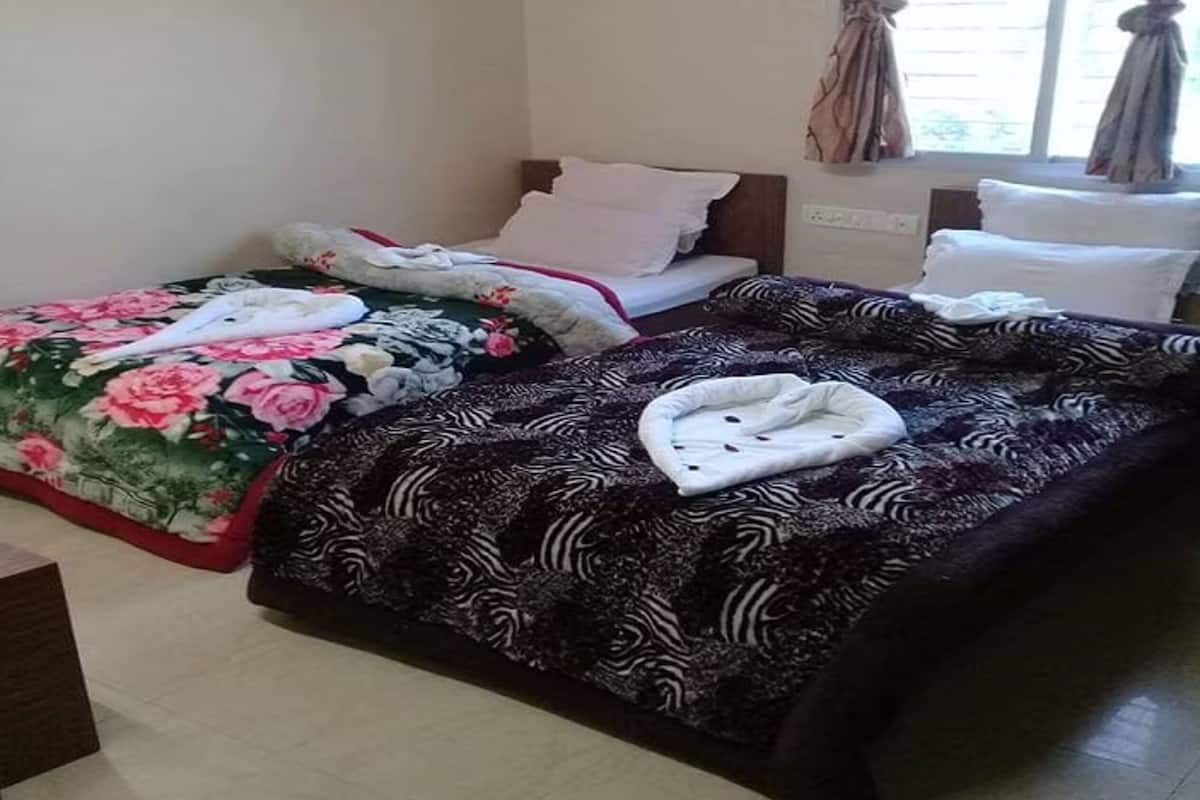 A hotel room with two beds, each with a distinct patterned bedspread.