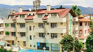 A multi-story hotel with balconies, a swimming pool, and a view of mountains. - Green Palm Hotel (Marmaris)