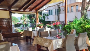 An outdoor dining area with tables and chairs, surrounded by potted plants and flowers. - Green Palm Hotel (Marmaris)