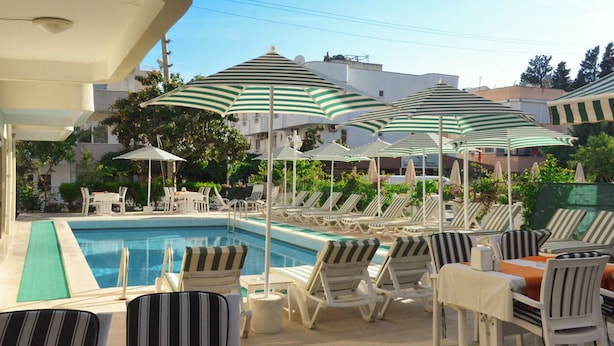 A poolside area with striped umbrellas, lounge chairs, and a swimming pool. - Green Palm Hotel (Marmaris)