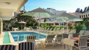 A poolside area with striped umbrellas, lounge chairs, and a swimming pool. - Green Palm Hotel (Marmaris)
