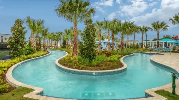 Ein geschwungener Pool mit umliegendem Garten und Palmen.