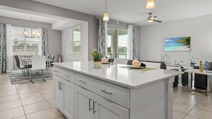 A modern kitchen with a large island, white cabinetry, and pendant lighting. - Cozy & Stylish 2BR Condo, Prime Storey Lake Spot (Kissimmee)