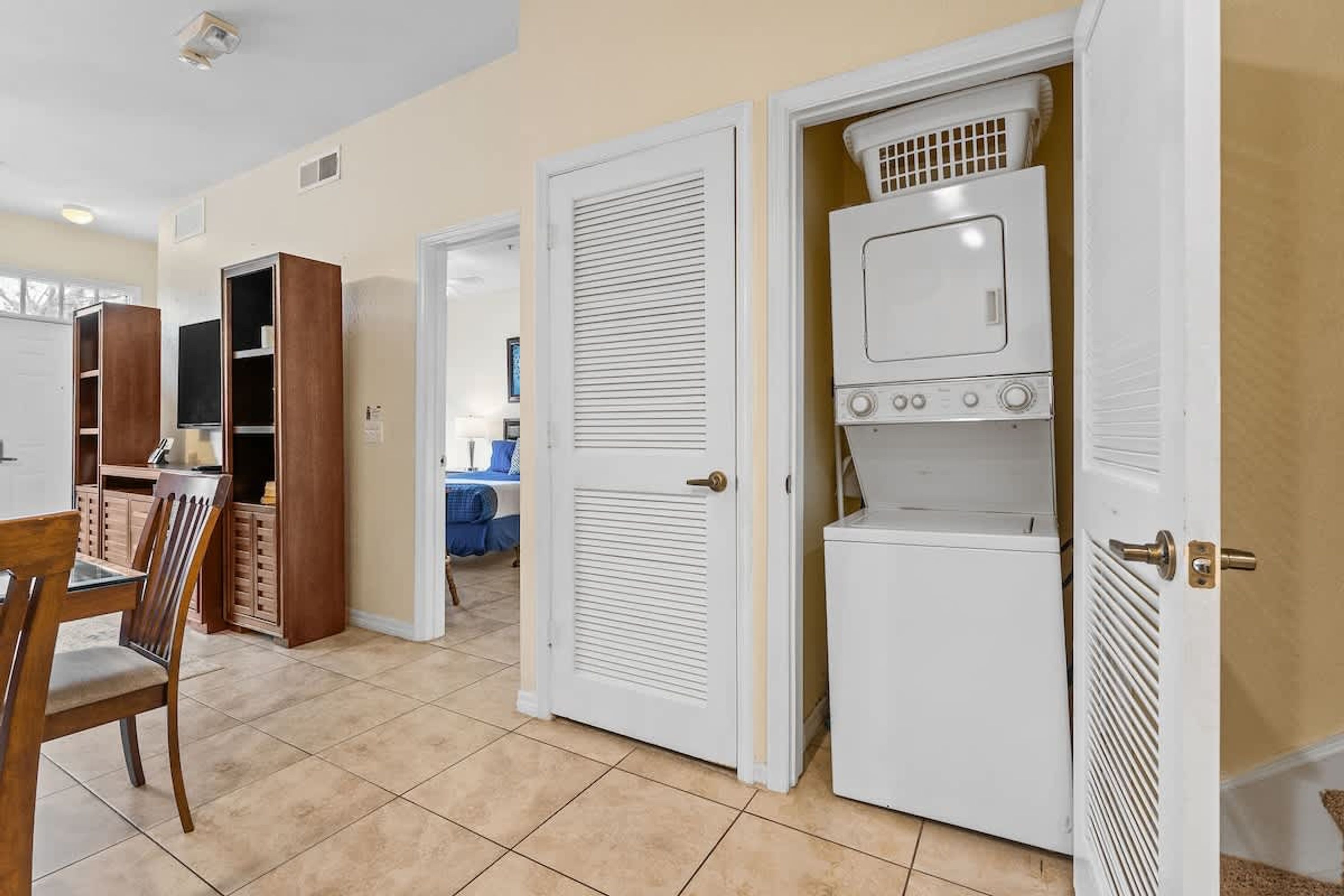 A room with a dining table and chairs, a white door, and a laundry area with a dryer and washing machine.
