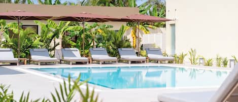 Un espace piscine équipé de chaises longues et de parasols.