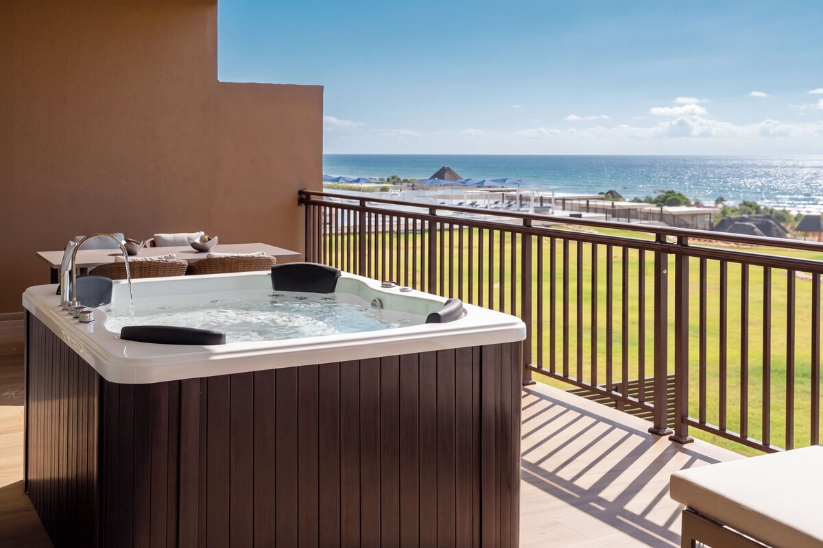 A hot tub on a balcony with a view of the ocean.