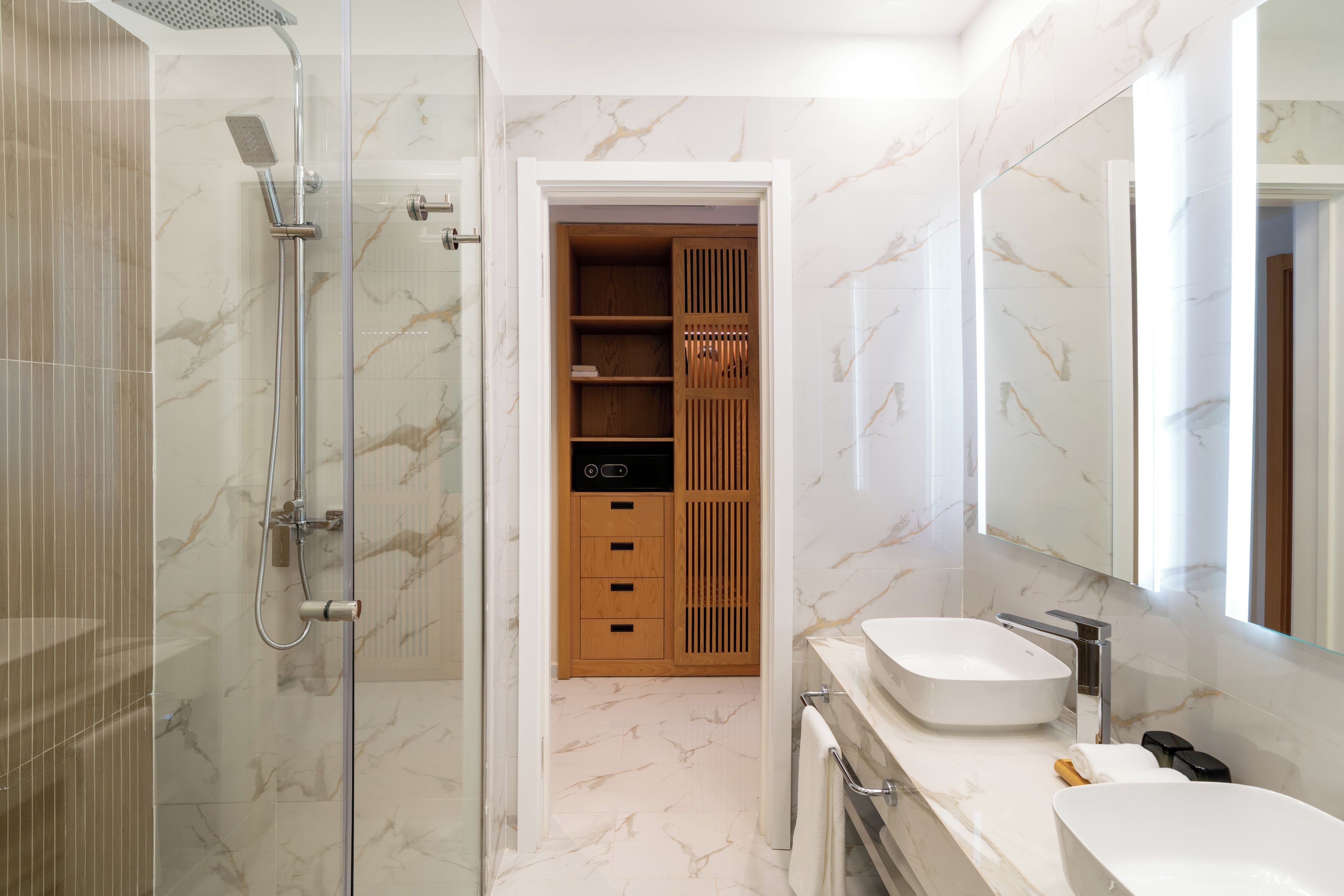 A modern bathroom with a glass-enclosed shower, a wooden vanity with a sink, and a built-in cabinet.