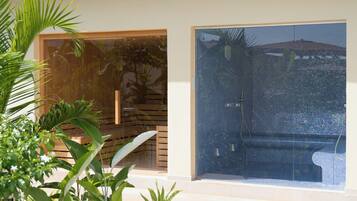 A modern outdoor pool area with a glass enclosure, surrounded by lush greenery.