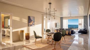 A modern hotel room with a dining area, a living room with a view, and a balcony.