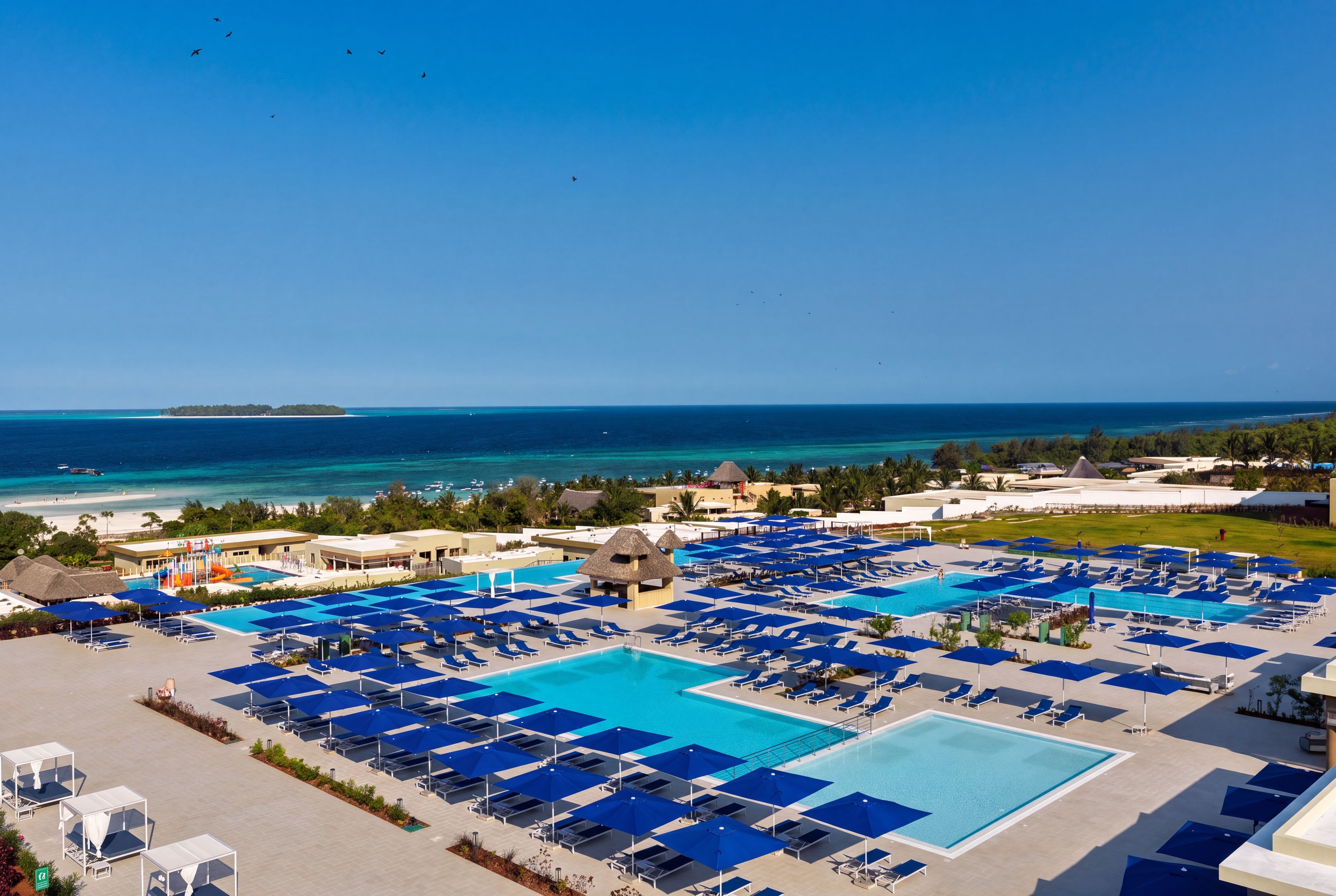 Un complex turístic amb diverses piscines, zones d'esbarjo i vista a l'oceà.
