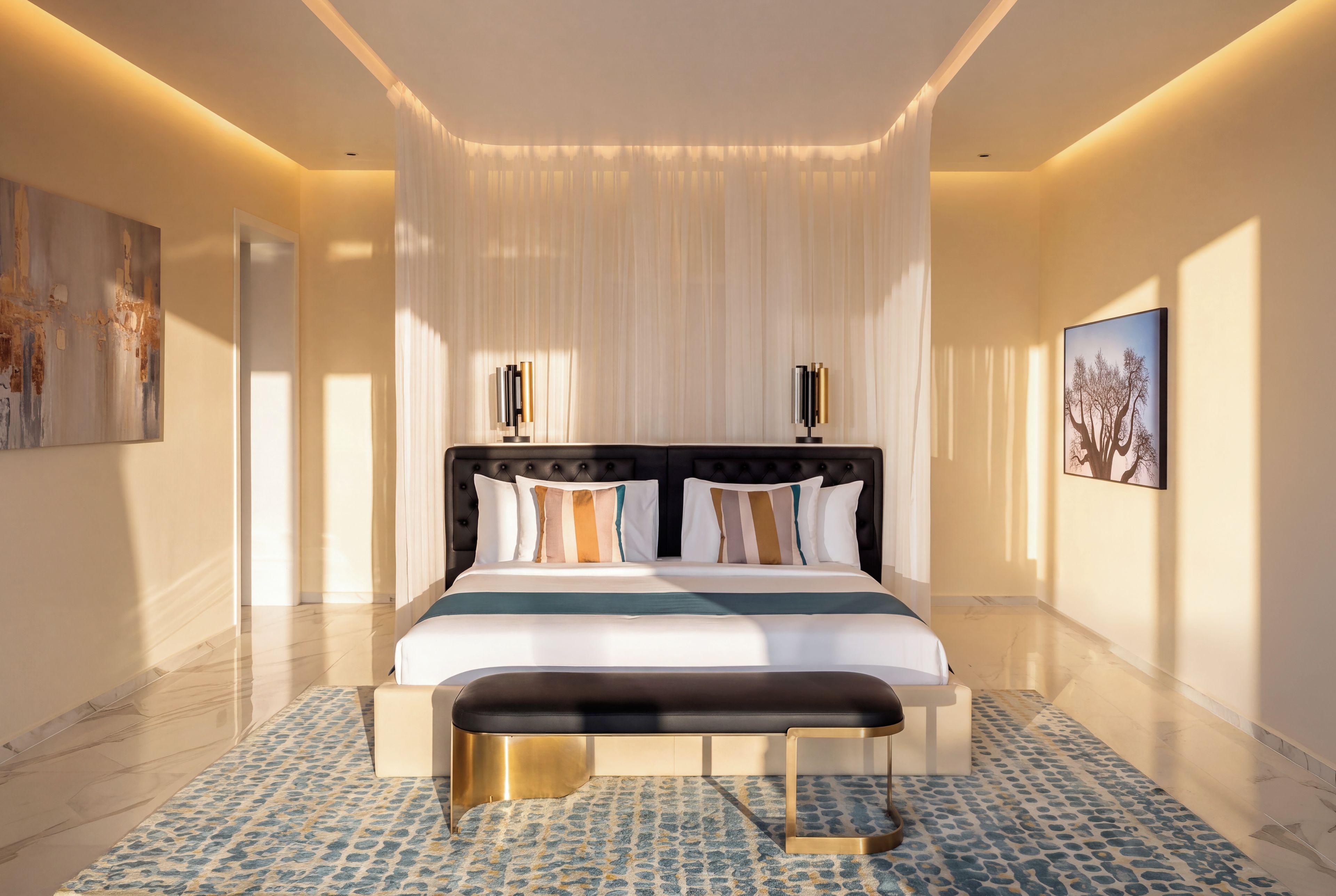 A modern bedroom with a large bed, a bench, a decorative wall, and a painting.