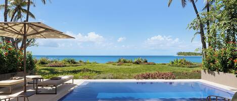 A poolside area with lounge chairs, a table with a notebook, and a view of the ocean.