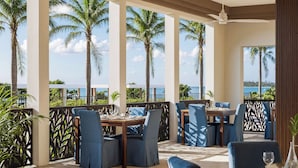 A restaurant with outdoor seating, palm trees, and a view of the sea. - Iberostar Selection Zanzibar – All-Inclusive (Matemwe)