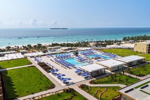 A resort with multiple swimming pools, a beach, and a view of the ocean.