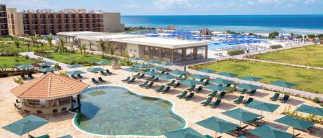 A resort with a swimming pool, lounge chairs, and a view of the ocean.