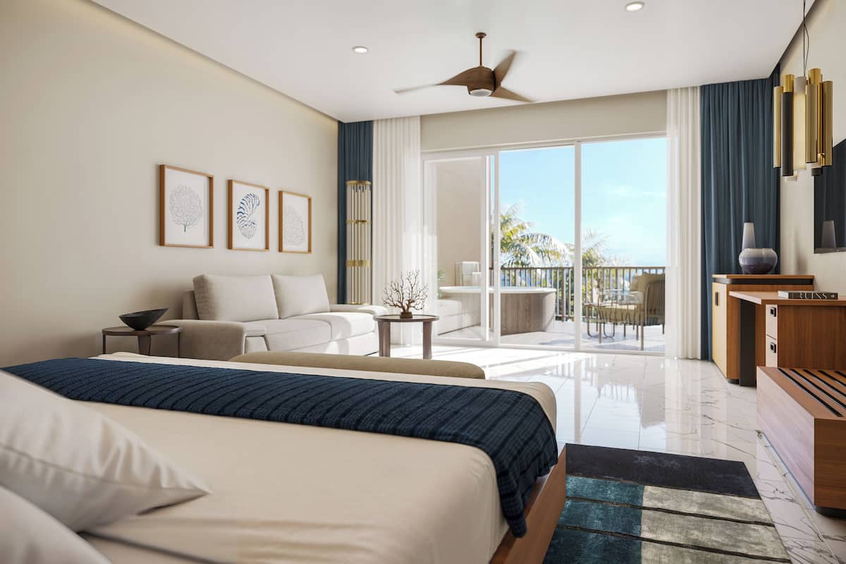 Una habitación de hotel moderna con cama, sofá, balcón con mobiliario exterior y ventilador de techo.