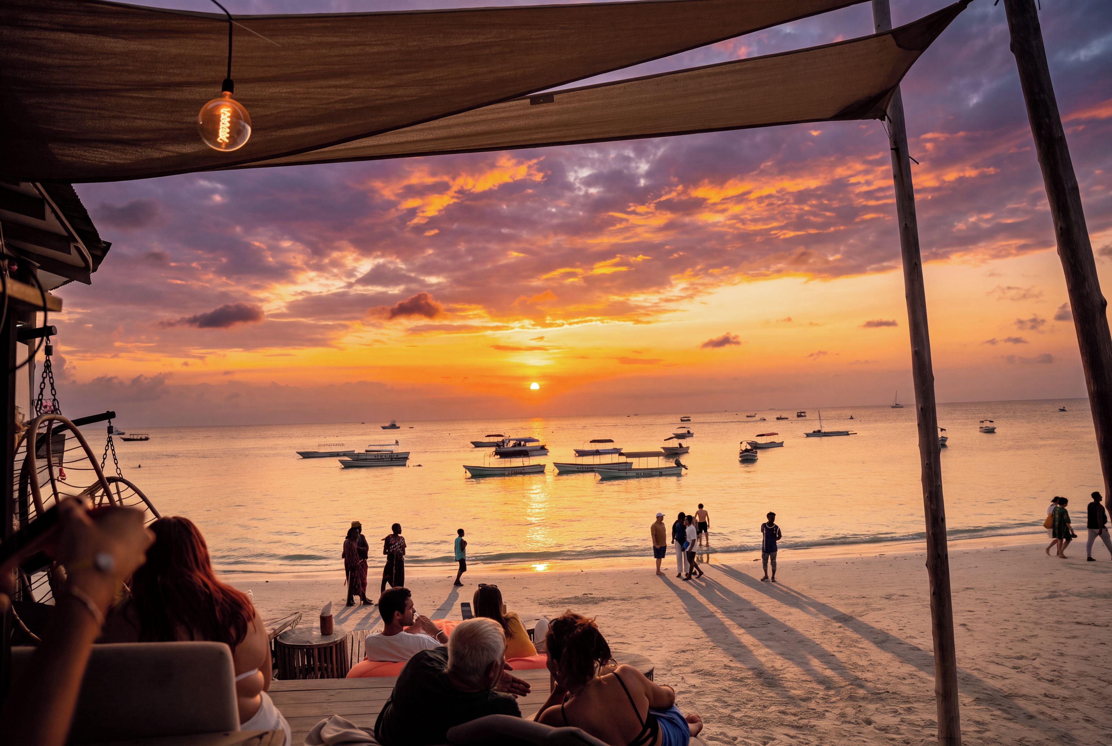 A beach scene with a sunset, boats, and people on the sand.